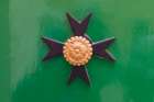 Malta, Birgu. Maltese Cross plaque on a green wall. Art Print